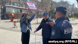 "Олар біздің сайлауымызды ұрлап алды" деген жазу ұстап, наразылығын білдіріп жалғыз өзі пикетте тұрған қызды әкетуге келген полиция қызметкерлері. Алматы, 26 наурыз, 2023 жыл. Азаттық архивіндегі фото