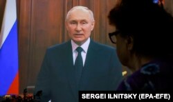 Женщина смотрит телеобращение президента России Владимира Путина. Москва, 24 июня 2023 года