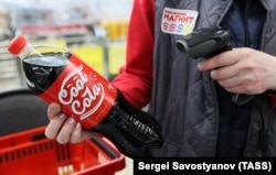 Россия. Москва. Сотрудник держит в руках газированный напиток CoolCola на кассе в магазине "Магнит" на Изумрудной улице, май 2022 года