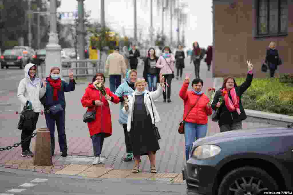 Жанчыны вітаюць кіроўцаў машын, якія ім сыгналяць