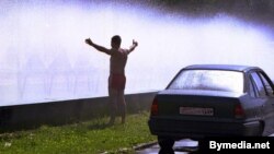 Belarus -- The young man refresh himself and his car in a cloud of spray from the fountain