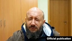 Асуджаны Вадзім Дзмітронак падчас аператыўнай здымкі з залітымі газам вачыма. Скрыншот зь відэа.