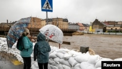 Людзі з парасонамі стаяць ля берага ракі Бялка ў Глухалазах, Польшча, 14 верасьня 2024 