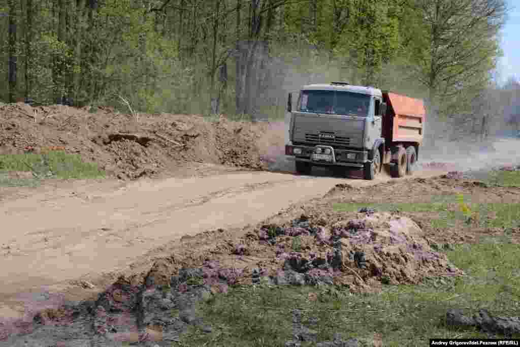 КАМАЗ свозит грунт, снятый с дороги, на лужайку.&nbsp;