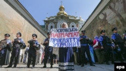 Фото более позднего периода. Украинка держит плакат с лозунгом «Московский патриархат – это проклятие для Украины!» во время протеста перед кордоном милиции возле входа в Киево-Печерскую лавру. Киев, 13 августа 2014 года