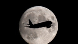 A passenger plane passes in front of the moon as it makes its final landing approach to Heathrow Airport in London, Britain September 12, 2019. 