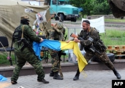 «Восток» батальонының сарбаздары Донецк қаласындағы облыстық әкімдіктен Украина туын алып шығып, жыртып жатыр. Донецк, 29 мамыр 2014 жыл.